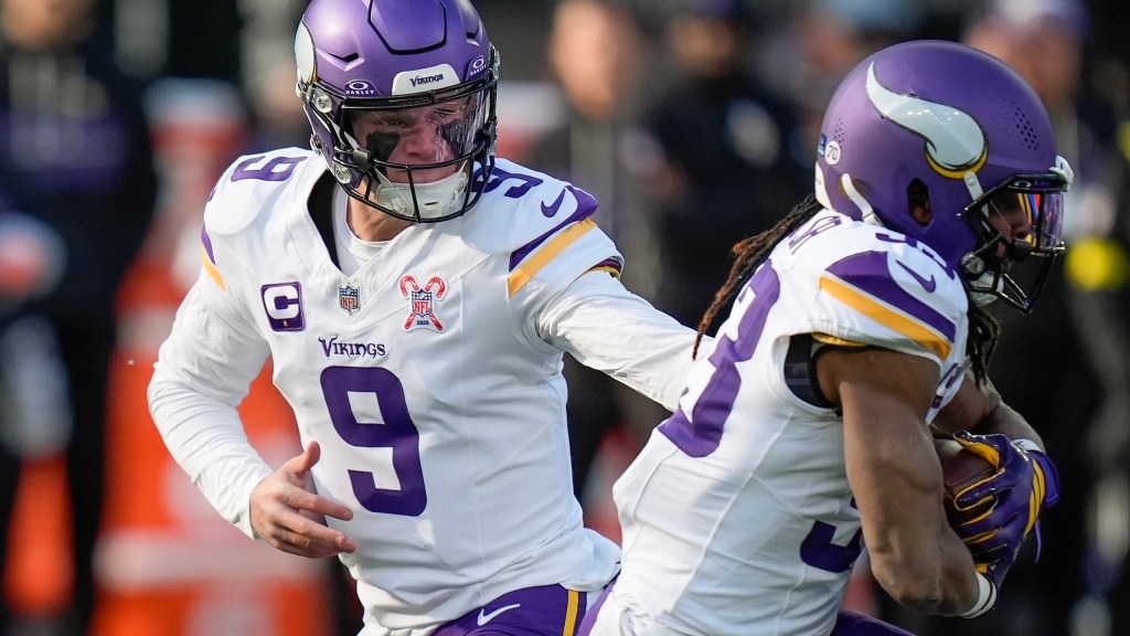 J.J. McCarthy handing off the football to Aaron Jones as members of the Minnesota Vikings
